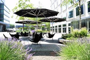 苏黎世苏黎世普莱西德设计与生活方式酒店的一组椅子和遮阳伞在建筑前