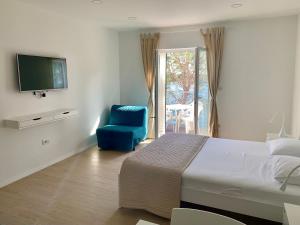 拉布Apartments Kaldana的一间卧室配有一张床、一张蓝色椅子和电视。