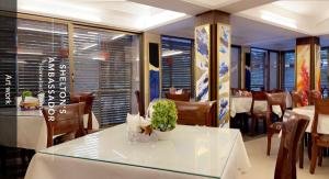 伊斯兰堡Shelton's Ambassador的餐厅设有白色的桌子、椅子和窗户。