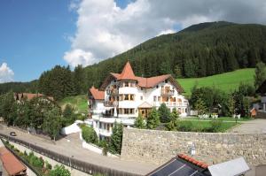 瓦莱迪卡谢斯Turmhotel Gschwendt的一座白色的大房子,拥有石墙和山