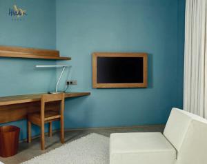滨海卡约Hidden Bay Hotel的蓝色的客房配有书桌和墙上的电视