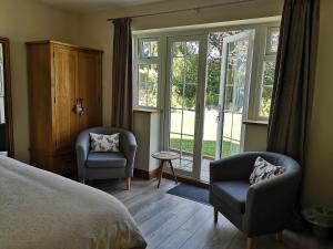 SpilsbyWhite Cottage B and B的一间卧室配有一张床、两把椅子和窗户