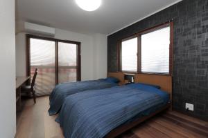 名古屋ROYAL SUITE SAKAE - Vacation STAY 11483的一间卧室配有一张蓝色棉被和两个窗户。