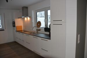 温特贝格Vakantiehuiswinterberg的厨房配有白色橱柜、水槽和窗户。