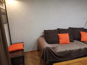 蒙乃第耶-勒潘Residence le Cairn的一张沙发,里面摆放着橙色枕头