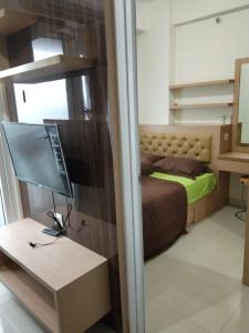 雅加达Apartemen Green Pramuka City的一间卧室配有一张床和一张书桌及电视