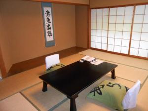 伊豆新井旅馆 的一间设有黑桌子和两把椅子的房间