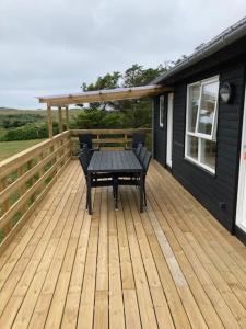 洛肯Gl. Klitgaard Camping & Cottages的木甲板上配有桌子和长凳