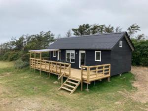 洛肯Gl. Klitgaard Camping & Cottages的黑色的小房子,设有大型木甲板