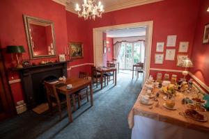 巴纳德城堡Homelands Guest House的一间拥有红色墙壁和桌子以及壁炉的用餐室