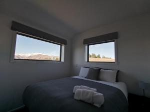 特卡波湖Skyrim Lodge的一间卧室设有一张大床和两个窗户