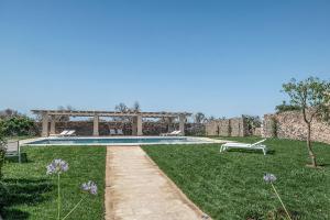 梅伦杜尼奥Masseria Berzario的一座位于庭院中间的游泳池,设有石墙