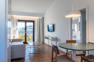 马翁Calallonga Hotel Menorca的一间带桌子的客厅和一间餐厅