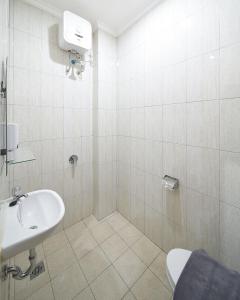 雅加达Heritel Urban Hostel的白色的浴室设有水槽和卫生间。