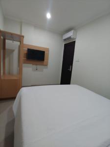 雅加达Heritel Urban Hostel的卧室配有白色的床和电视。