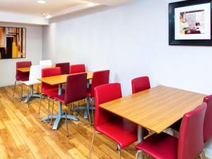 特伦特河畔伯顿ibis budget Burton Upon Trent Central的一间会议室,配有木桌和红色椅子