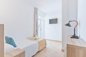 伊维萨镇Suncoast Ibiza Hotel - Adults Only -的一间卧室配有一张床、一张桌子和一盏灯