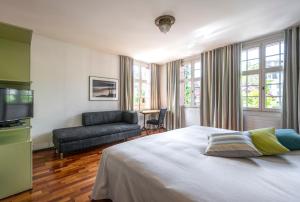 卢塞恩霍夫加藤卢泽恩酒店的一间卧室配有一张床、一张沙发和一台电视