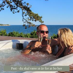 伦讷Fredensborg Badehotel的男人和女人在热水浴缸中戴香槟杯