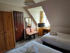 托明陶尔Richmond Arms Hotel的一间卧室配有两张床、一张桌子和一把椅子