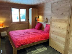 蒙乃第耶-勒潘Chalet Serre Chevalier的木制客房内的一张红色床
