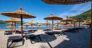 内乌姆Marea Hotel & Spa的沙滩上一束草伞和椅子