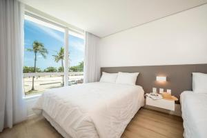 马塞约Hotel Praia Bonita Jangadeiros Pajuçara的白色的卧室设有一张大床和一个窗户