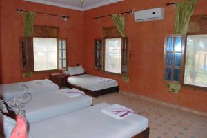 Oulad TeïmaGite Souss的客房设有三张床、窗户和红色墙壁。