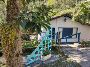 伊泰帕瓦Vila da Sol Itaipava casas e estúdios的房子前的树旁的蓝色楼梯