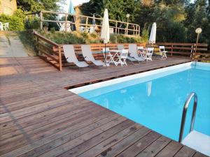 芬奇Le Mimose B&B的一个带椅子的木制甲板和游泳池