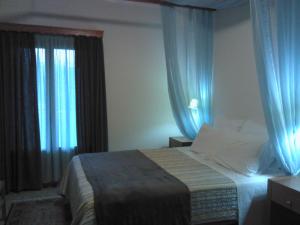 卡尔派尼西翁Menta( Archontiko Machalioti )的一间卧室配有一张带蓝色窗帘的大床