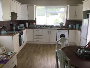 恩尼斯基林TJ’s Cottage的厨房配有白色橱柜、桌子和水槽。