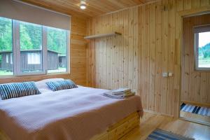 UznezyaАйбарка的木制客房内的一间卧室配有一张大床