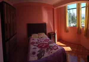 万卡约La Azotea的一间卧室配有一张带花卉床罩的床和窗户。