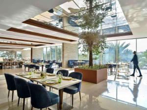迪拜Rixos The Palm Luxury Suite Collection - Ultra All Inclusive的一间设有桌椅的餐厅,以及一位在后面散步的人