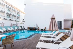 赫索尼索斯Kahlua Boutique Hotel的酒店游泳池设有白色躺椅和台球桌