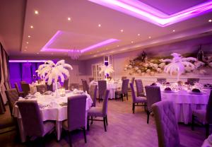 威赫罗伏Dworek Rajska Góra的宴会厅配有白色的桌椅和紫色的灯光