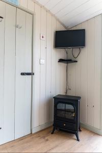 彻奇斯特雷顿Hilltop Hut的一间带炉灶的房间和墙上的电视