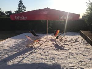 埃尔姆山麓克尼格斯卢特尔Hotel zur Post Ochsendorf的沙滩上的三把椅子和一把遮阳伞
