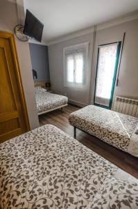 坎德莱达Hostal La Pastora的客房设有两张床、一台电视和两个窗户。