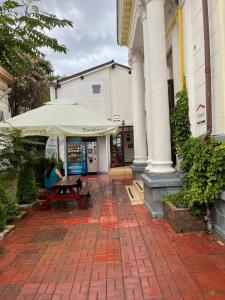 布加勒斯特Piata Uniri Cozy Inn的大楼前带雨伞的野餐桌