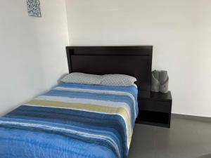 蒙特雷Departamento en Edificio El Semillero的一张带黑色床头板和蓝色毯子的床