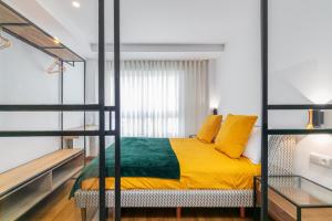 维戈SUITE LUJO CENTRO-NAUTICO-CIES+parking的一间卧室配有一张带黄色和绿色床单的双层床