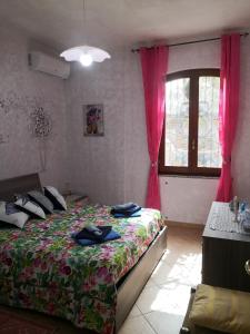贡内萨Il Bronzetto的一间卧室配有床和一个带粉红色窗帘的窗户。