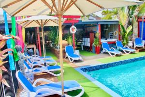 佩里吉安比奇亥努沙男性专用海滩度假酒店的房屋旁的游泳池配有椅子和遮阳伞