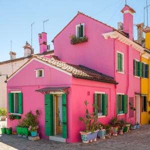 布拉诺岛Night Galleria holiday home - bed & art in Burano - the pink house的粉红色的房子,街上有绿门