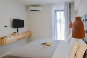 纳克索乔拉Princess Mare Hotel - Adults Only的一间卧室配有带帽子的床和电视。