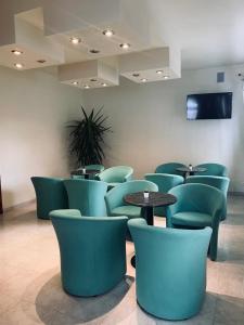 卡奥莱Hotel Al Capitano的一间设有绿色椅子和桌子的等候室