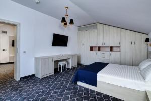 北马马亚-讷沃达里Eros Beach Resort的一间卧室配有一张床、一张书桌和一台电视。