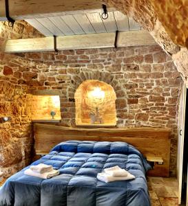 阿尔贝罗贝洛特鲁利普利亚度假旅馆的一间卧室,在石墙内配有一张蓝色的床
